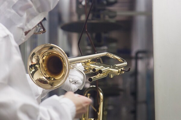 A worker cleaning a musical instrument during the washing process at a Yamaha factory.