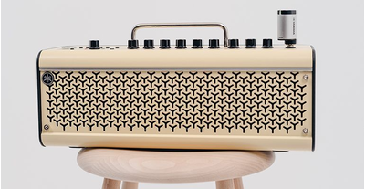 The THR30II Wireless guitar amp that the YW10T is plugged into its input jack is on the wooden stool, on a gray background.
