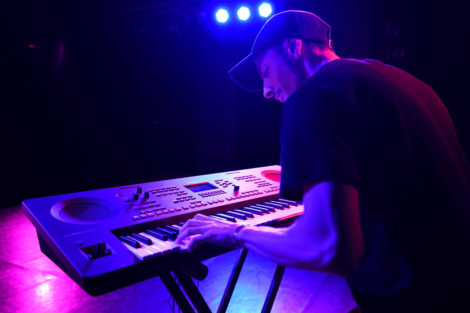 Músico tocando un Arranger Workstation Yamaha en un soporte bajo la iluminación del escenario