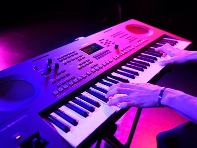 Primer plano de unas manos tocando un teclado durante una presentación en vivo.