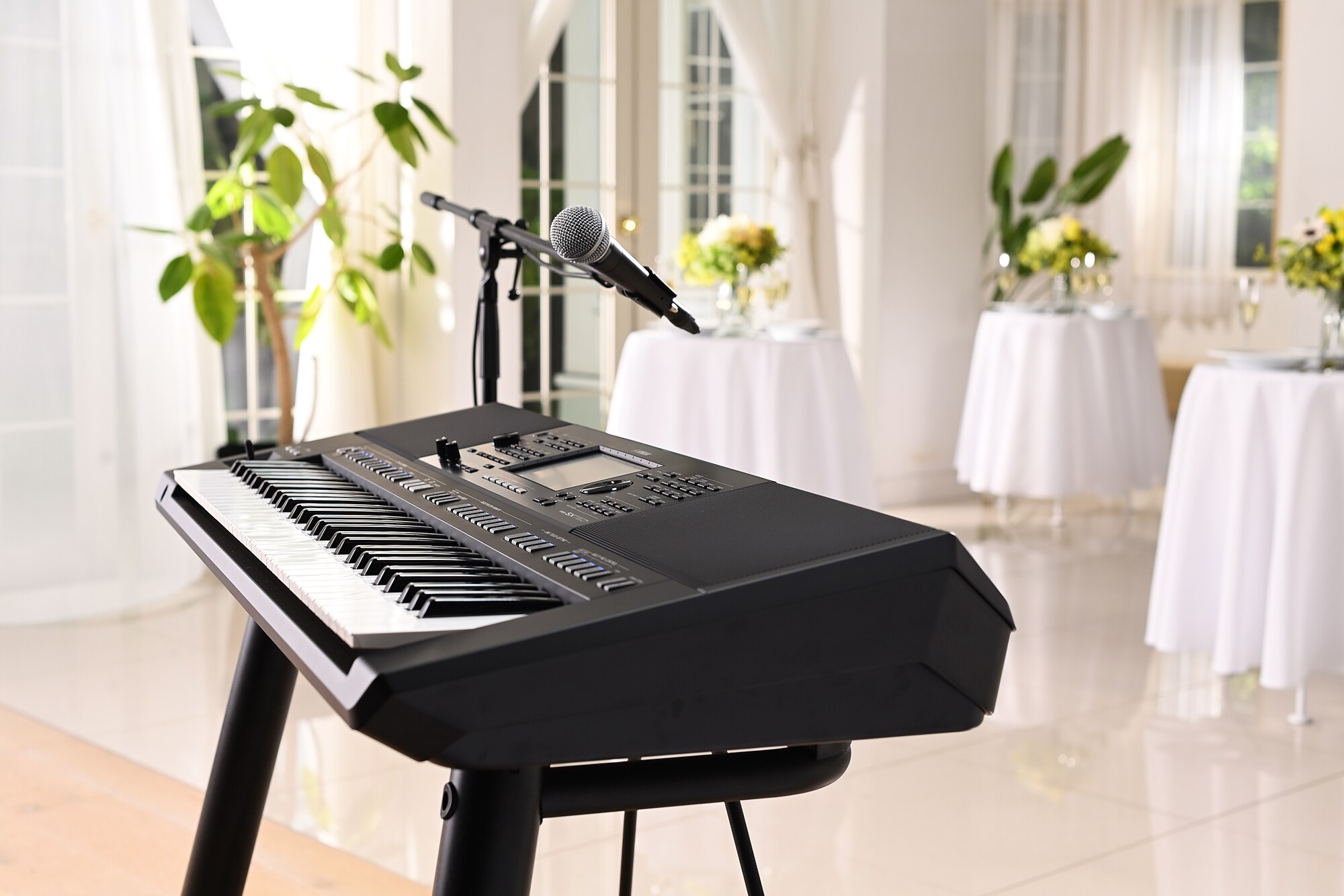 Estación de trabajo de arreglos Yamaha PSR-SX720+ con soporte de micrófono en un salón de fiestas