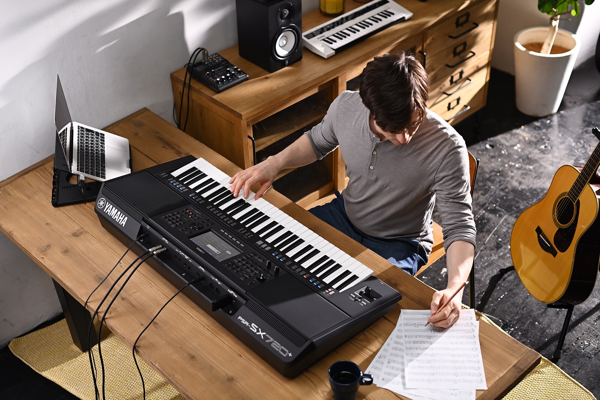 Foto de una persona escribiendo en una partitura mientras toca la estación de trabajo de arreglos Yamaha PSR-SX720+