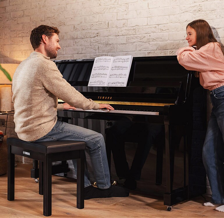 Una madre y su hija disfrutan tocando el piano vertical serie B