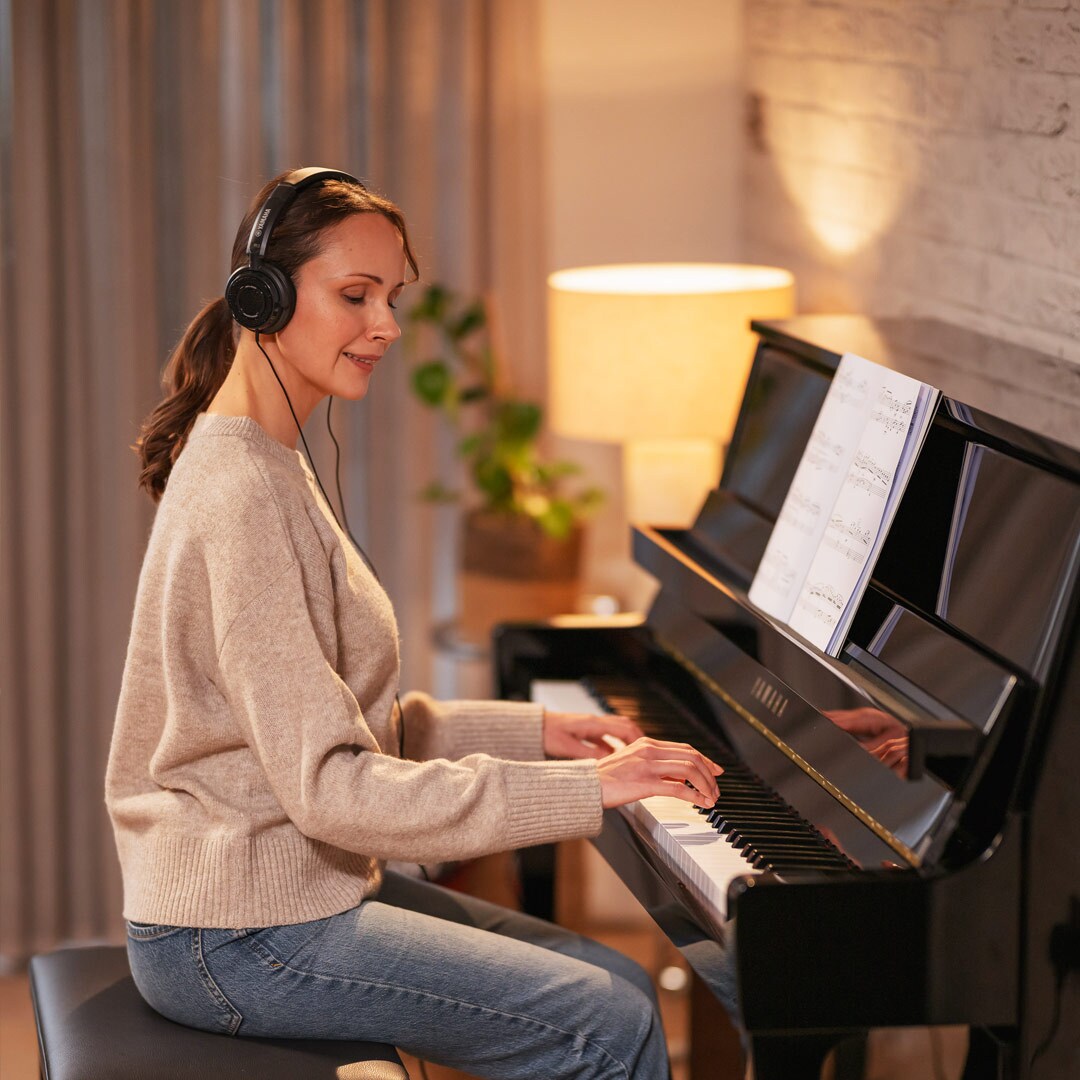 Una mujer disfruta tocando el piano usando audífonos