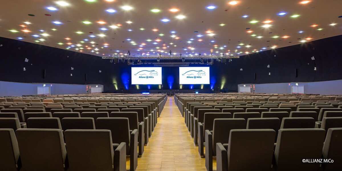 Gran auditorio en Allianz MiCo en Milán con gradas, dos pantallas de presentación y un sistema de sonido integrado de Yamaha Pro Audio para conferencias y eventos.